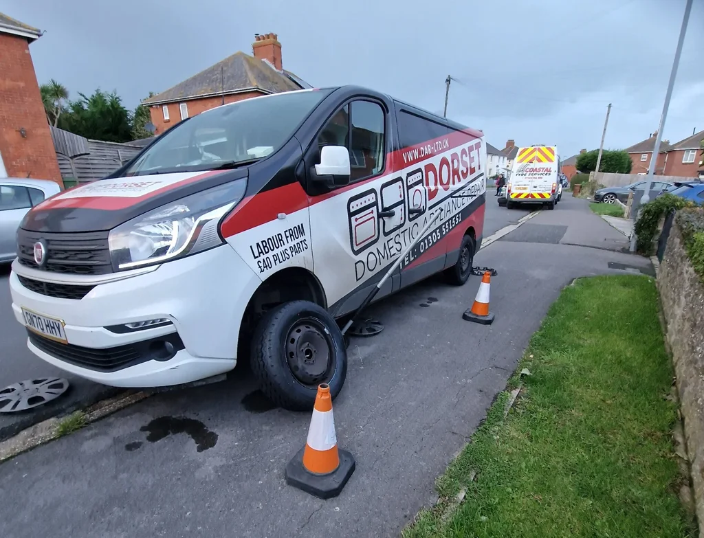 Commercial van parked on a residential street in Weymouth with branding for a mobile tyre fitting company, flanked by traffic cones.