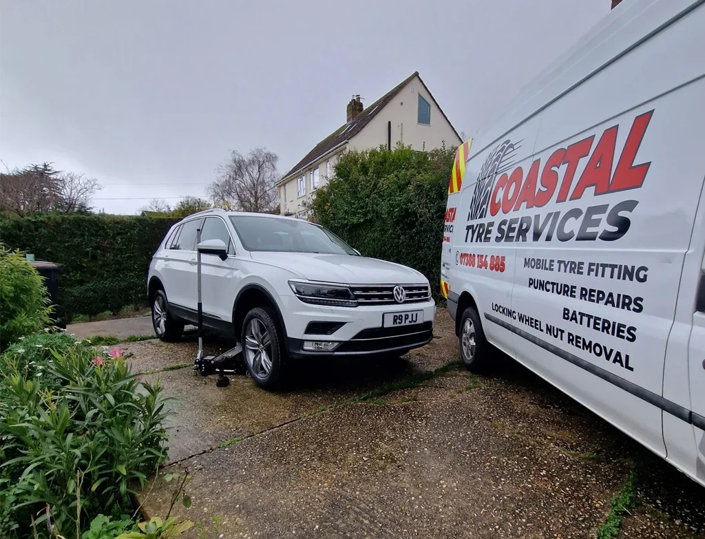 A white suv parked in a driveway next to a van offering mobile tyre fitting services in Weymouth.