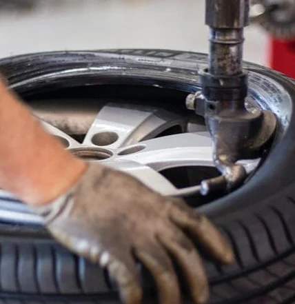 A mechanic's gloved hand working on a tire installation or repair at Coastal Tyre Services.