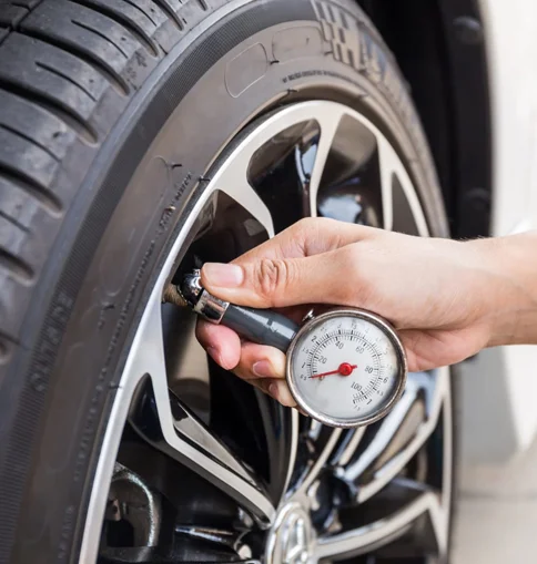 Checking tire pressure with a gauge at Coastal Tyre Services.